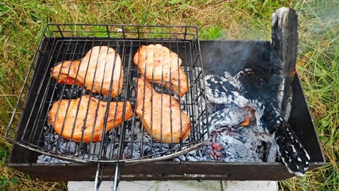 Closeup of marinated big turkey or chicken meat steak shashlik or shish kebab preparing cooking on barbecue brazier grill over charcoal on burning coal. Skewered roasted kebabs on BBQ grill.
