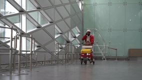 Young smiling African American man pushing luggage trolley while walking after arrival at airport, talking on mobile phone. Happy Black male tourist rolling a baggage cart in terminal. Trip, journey. - Powered by Shutterstock - Get 15% off with code: PIKWIZARD15