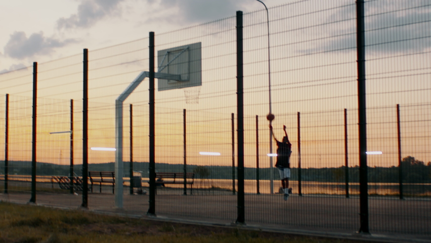 Black African American teenager kid boy playing basketball alone on an outdoor court in the evening. High quality 4k footage | Shutterstock HD Video #1090263309