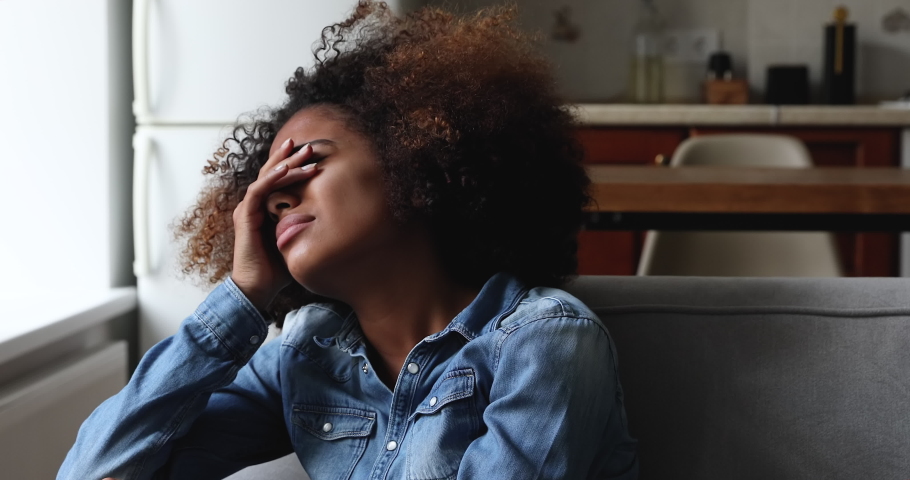Crying frustrated young African woman sit on sofa alone suffer of psychological trauma personal drama make difficult decision think on abort. Worried stressed millennial lady feel lonely after divorce | Shutterstock HD Video #1090263759