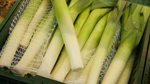 Many beautiful leeks in a trading box and a male hand takes one