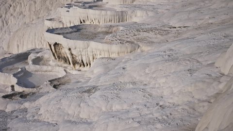 Lacy white travertine formations at hot springs of cotton castle of Pamukkale on sunny day, Turkey