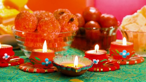 Colorful Diwali oil lamps, Deepavali oil lamps lighted in beautiful formation with bowls full of different Diwali sweets   Decorative Colorful Diya