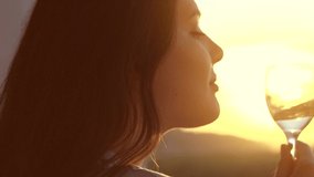 Beauty Young woman drinking white wine and enjoying sunset view on a terrace. Beautiful Caucasian girl holding glass of wine outdoors. Wine tasting. Enjoying of wine over sun light. Slow motion - Powered by Shutterstock - Get 15% off with code: PIKWIZARD15