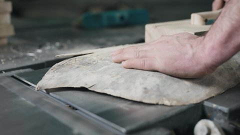 Close-up of hands and wood workpiece on planer. An unrecognizable man works as a carpenter.