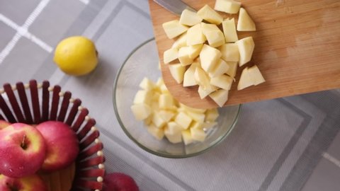 Apple pie preparation series - woman pours chopped apples into a glass bowl