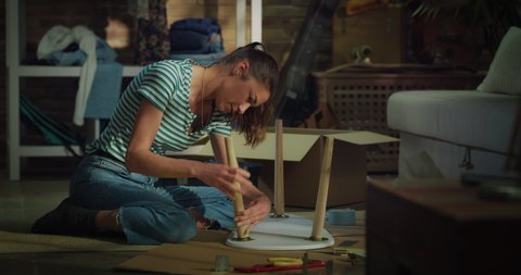 Cinematic shot of young creative woman is assembling wooden table to remodeling and renovation house by herself with diy techniques at home.