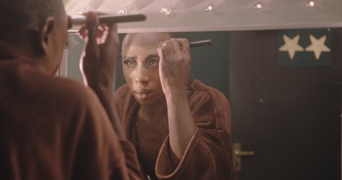 Non-Binary Person Applying Drag Queen Make-up Backstage, looking in Mirror Video de stock