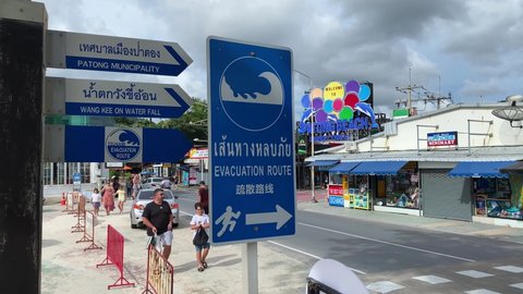 Phuket, Thailand - May 15, 2022: Tsunami evacuation route sign is seen in Patong Beach road, southeastern Thailand. The sign is written in Thai, English and Chinese language.
