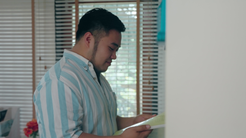 Fat Asian man packs up his stuff in preparation for moving into a new home and living a new life. adult male Enjoy reading a diary or an old book with good memories at houses. history concept