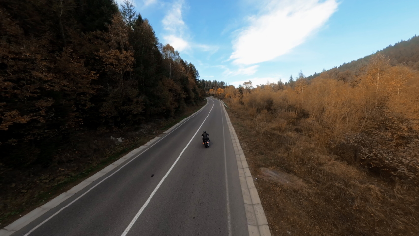 Motion FPV video of lonely motorcycle rider driving on empty highway in picturesque natural landscape. Concept for freedom, movement and travel. Royalty-Free Stock Footage #1090277659