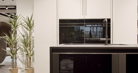 Modern white wooden kitchen room furniture. Elegant, Comfortable and Minimalist Home. Domestic Kitchen with modern black sink. Modern Kitchen room with minimalist dining table. Modern Minimalist Home.