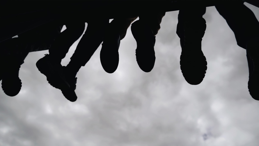 Children sit on the edge of the ledge with their legs hanging down, relaxed. Silhouettes of legs against the sky | Shutterstock HD Video #1090279779