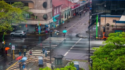 San Jose , San Jose , Costa Rica - 04 28 2022: Many pedestrians cross one of the main streets in the center of the city's capital during a rainy day