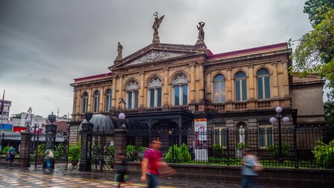 San Jose , San Jose , Costa Rica - 04 28 2022: People walk in front of the historical National Theater on a cloudy day
