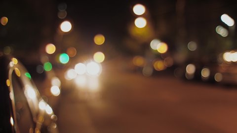 Blurred vision of city at night with traffic lights with a car passing by