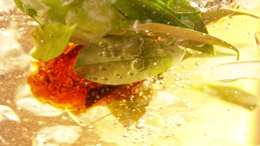 Super Slow Motion Shot of Pouring Tea into Whirl with Green Leaves and Ice Cubes at 1000fps. Royalty-Free Stock Footage #1090280903