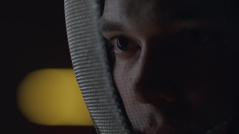 Extreme close up portrait of a fencer in a protective mask, preparing for the fight