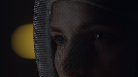 Extreme close up portrait of female fencer in a protective mask, preparing for the fight