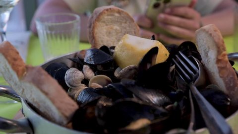 Clams and Mussels in Garlic Butter Wine Sauce. Traditional Italian lunch by the sea in a restaurant. Slow motion. High quality FullHD footage