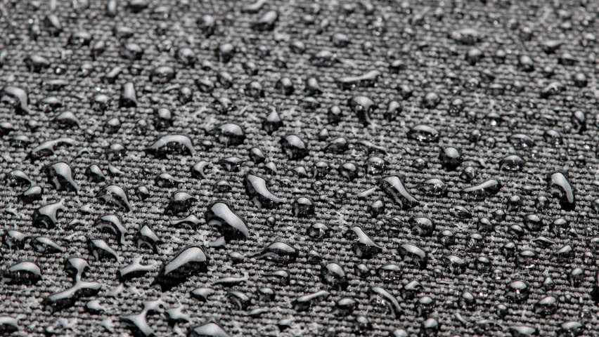 Spinning close-up background of black hydrophobic fabric, covered with water drops | Shutterstock HD Video #1090284907