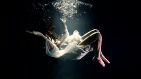 a girl in a white dress under the water mysteriously hangs in the rays of the sun as in a fairy-tale dream