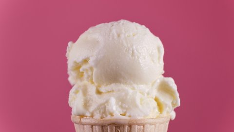 Timelapse of vanilla ice cream in waffle cone melting on pink background. Delicious white ice cream melting. Close-up of sweet dessert. 4K, UHD
