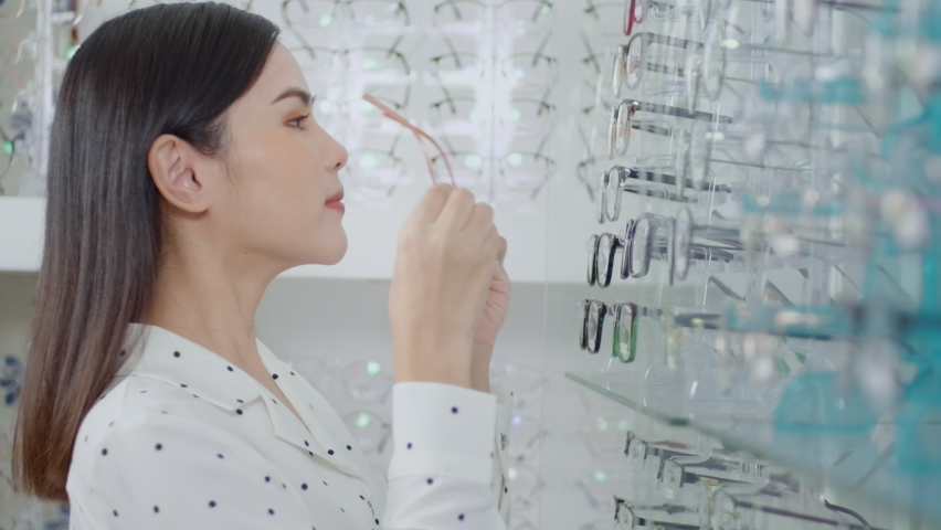 Young female customer choosing glasses in optical center, Eye care concept.

 Royalty-Free Stock Footage #1090290577