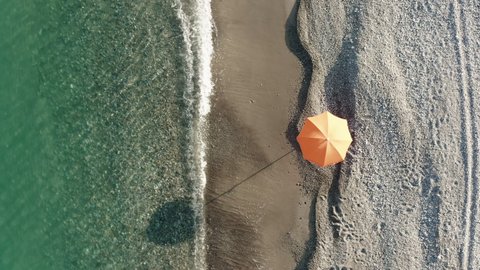 Orange umbrella near the calm waves of the sea at Summer