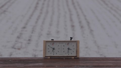 Belarus, Mogilev region, Bobruisk - March 20, 2022: Quickly pressing a button on a chess clock that stands on a table in a snowy field close-up