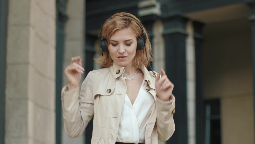 Liberated blonde in headphones dancing on the street | Shutterstock HD Video #1090291541