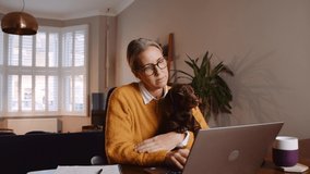 Caucasian female working from home holing pet dog