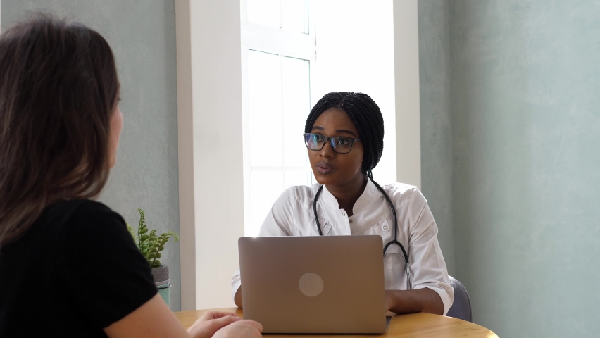 Friendly qualified female doctor in a white coat meets with a patient in the office. Doctor visit. Health care concept Royalty-Free Stock Footage #1090292841
