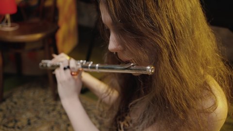 Musical hobby. Close up portrait of young talented lady musician playing flute at home, practicing new piece, tracking shot, slow motion