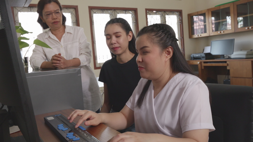 Wide angle shot of Asian women co-workers in workplace including person with blindness disability using computer with refreshable braille display assistive device. Disability inclusion at work concept | Shutterstock HD Video #1090294205