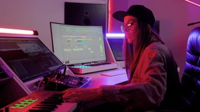 Woman in designer glasses, cap and headphones working in the recording studio with computer and mixer creating music. Music production studio concept - Powered by Shutterstock - Get 15% off with code: PIKWIZARD15