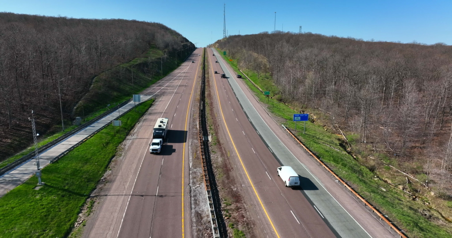 Interstate highway road up hill and through Mountains. Bare trees on winter day.