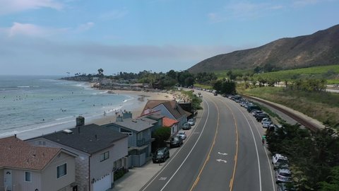 low aerial view of million dollar beachfront homes in Mondo Beach along the pacific coast highway route one on a sunny summer day as tourists enjoy the surf.