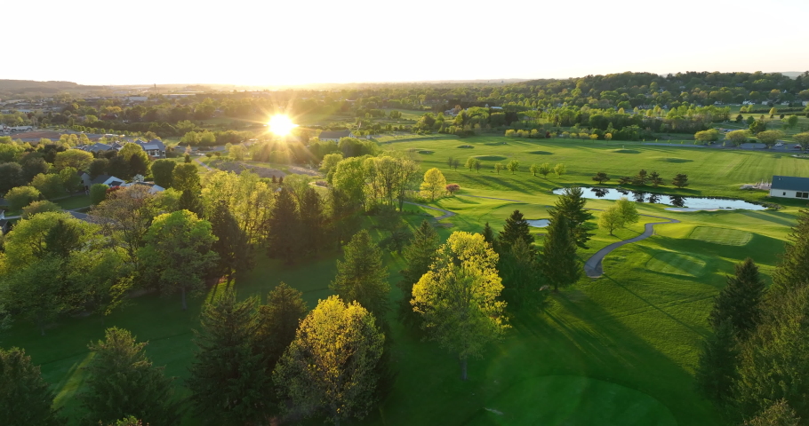 Aerial view of golf course green. Sunlight reflects during golden hour sunset. American country club culture. Royalty-Free Stock Footage #1090298437