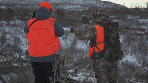 Two hunters observe the movement of deer on a hunting activity in winter. outdoor activities.