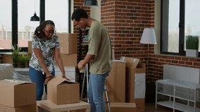 African american couple wrapping cardboard boxes with sticky tape to move in new apartment flat. Packing up furniture and home belongings in packages with adhesive roller for relocation. - Powered by Shutterstock - Get 15% off with code: PIKWIZARD15