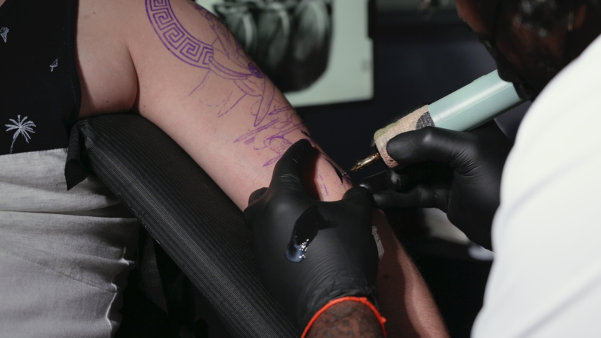 Professional tattoo artist makes a tattoo on a young man arm. High quality 4k footage | Shutterstock HD Video #1090304093
