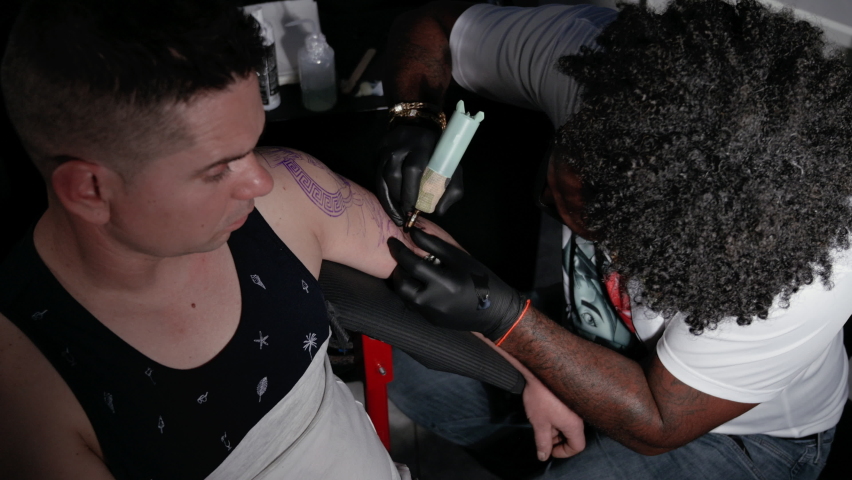 Professional African American tattoo artist makes a tattoo on client arm. High quality 4k footage. | Shutterstock HD Video #1090304655