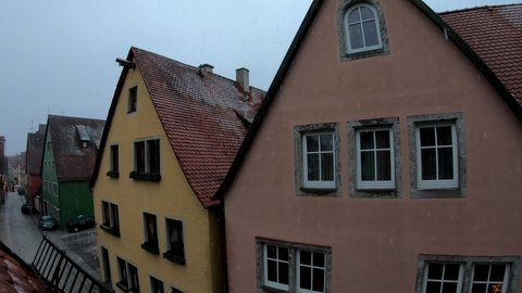 SLOW MOTION SHOT - Fairytale snowfall over the roofs in Rothenburg, Germany. Snow falls against the roof of German houses.
