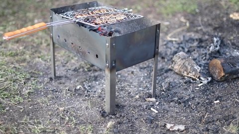 Meat on coals. Food in nature. Picnic details. Steel frame for fire. Brazier with net for meat.