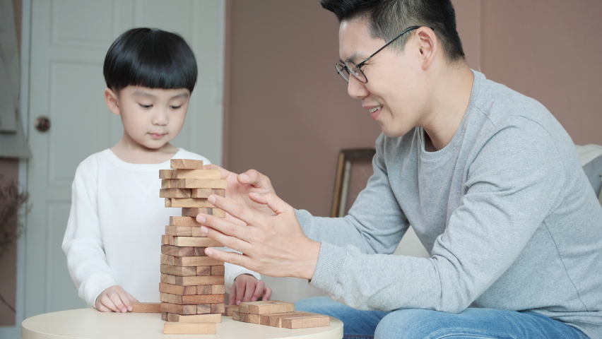 Happy family playing game building tower. Family man and kids boy happy expression with toys game while being quarantine at home. Stay at home family.