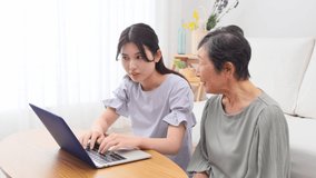 Asian granddaughter and grandmother using the laptop at home