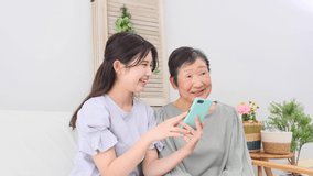 Asian granddaughter and grandmother using the smartphone at home