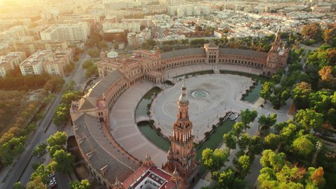 Flying over the Plaza de Espana at sunrise in Seville, Spain. Revealing aerial shot of the famous Spanish Square and Maria Luisa park in the morning in Seville. Slow tilt up 