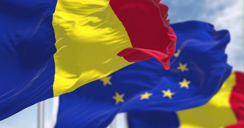 Seamless slow motion loop of the national flag of Romania waving in the wind with blurred european union flag in the background. Democracy and politics. European country. Selective focus